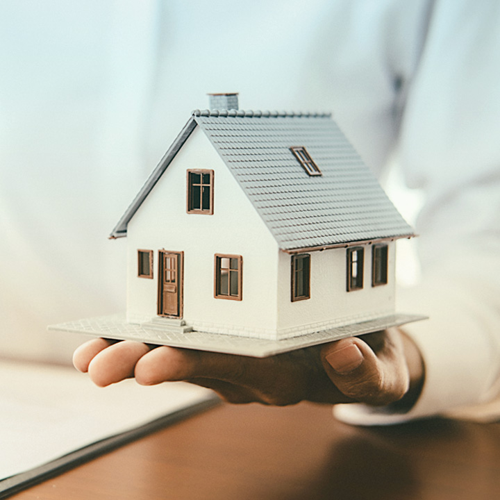 Photo of person holding model house in the palm of their hand