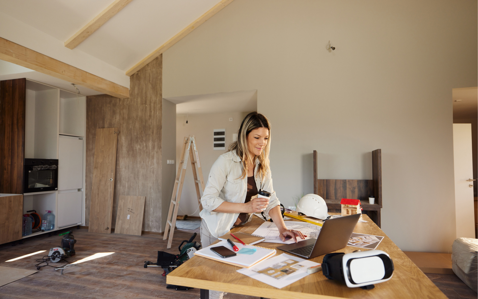 [A picture of a woman hoding a cup of coffee, reading instructions for how to repair her home on a laptop]